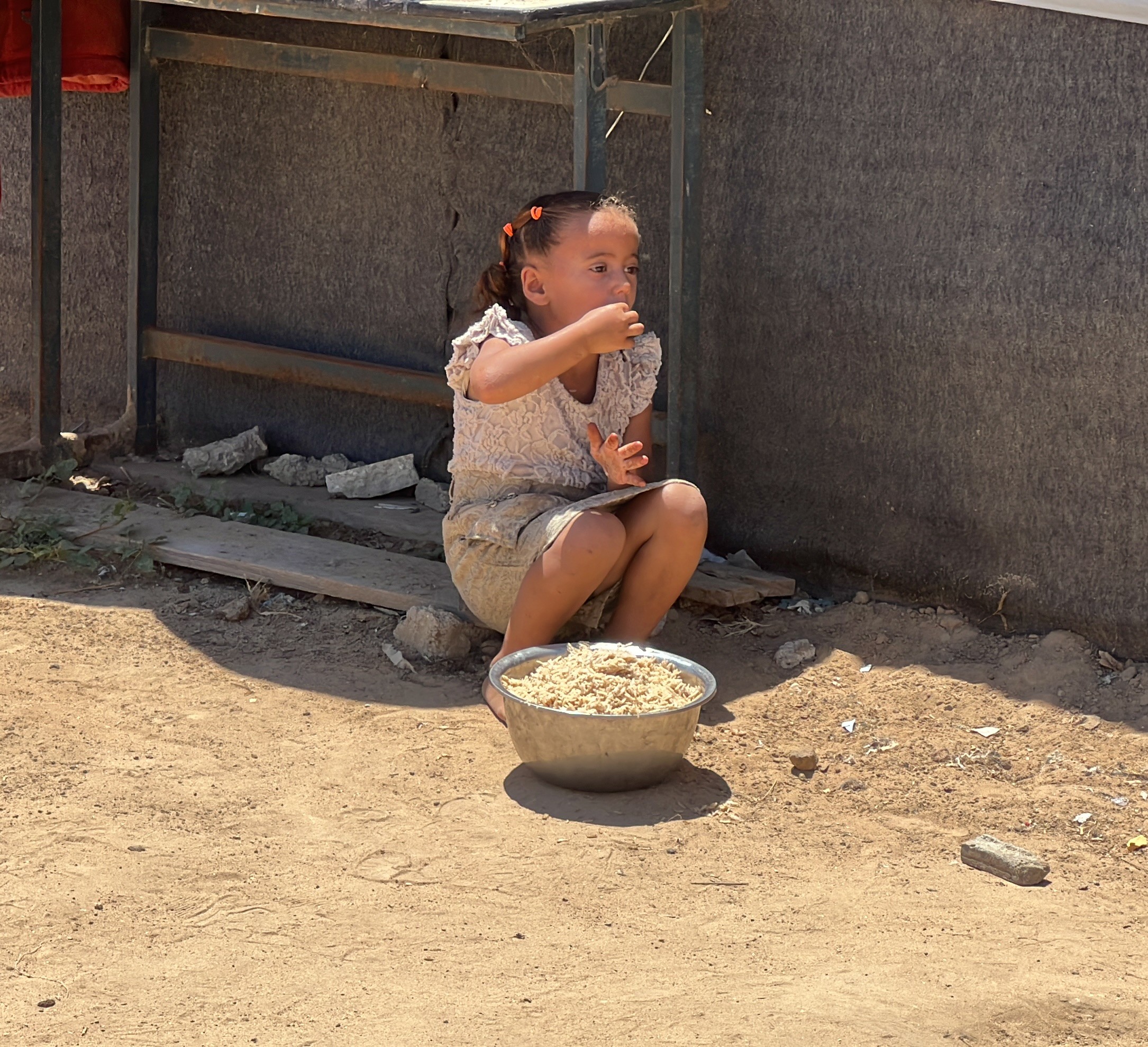 jeune fille mangeant dans un plat par terre en situation de famine en palestine