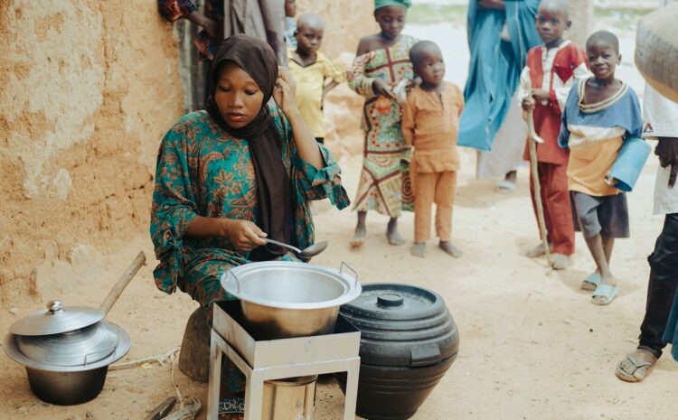 femme assise devant maison prépare repas pour plusieurs enfants